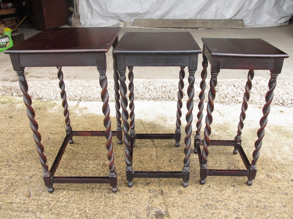 A nest of three dark oak square-topped side tables featuring carved barley twist legs and low stretchers. View VII