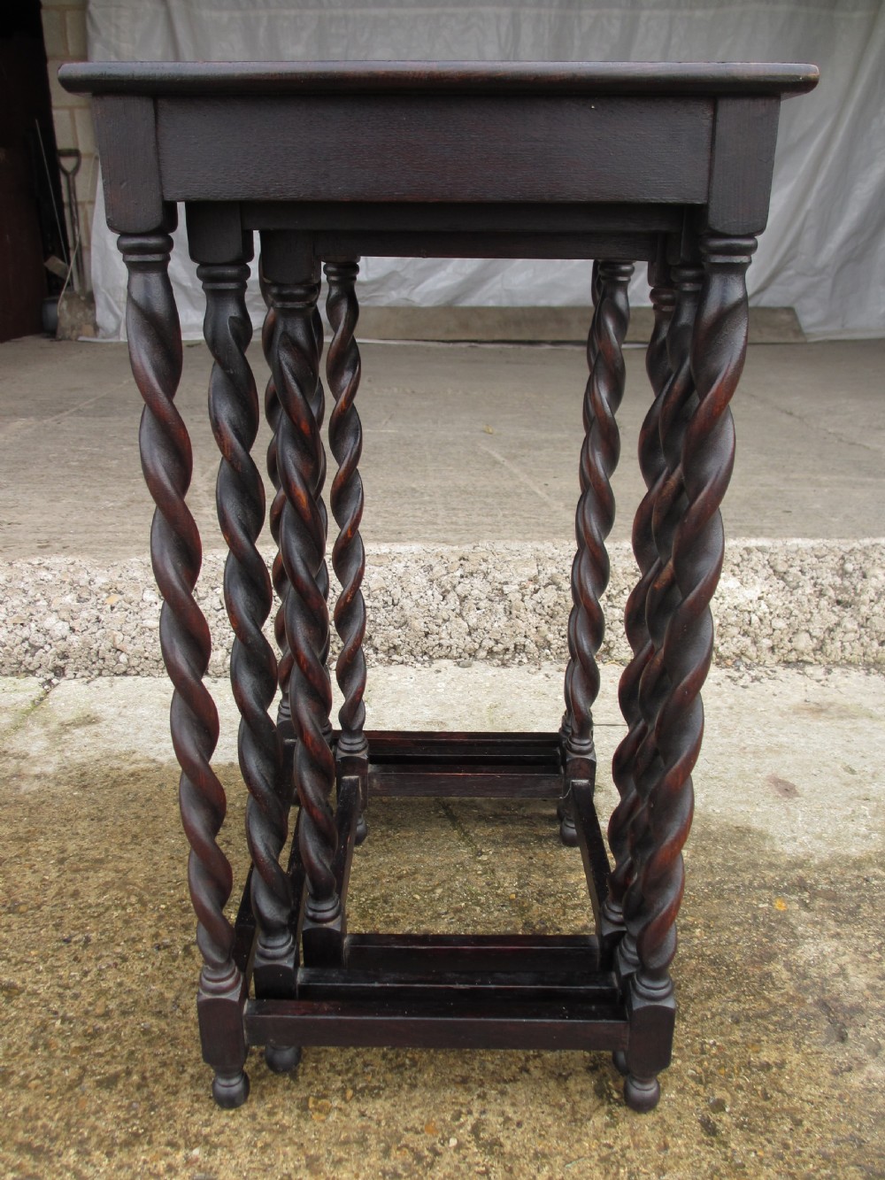 A nest of three dark oak square-topped side tables featuring carved barley twist legs and low stretchers. View X