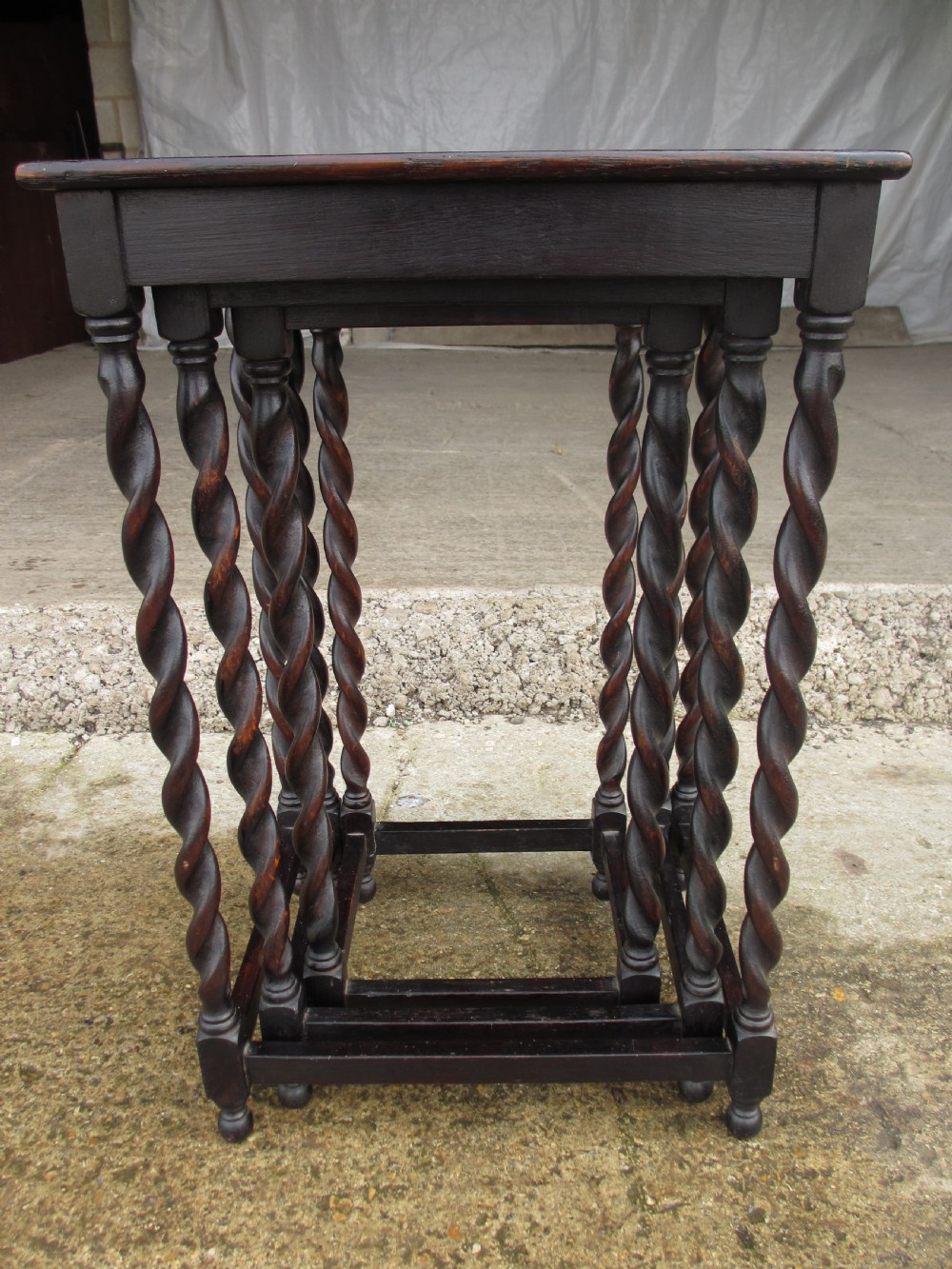 A nest of three dark oak square-topped side tables featuring carved barley twist legs and low stretchers. View XI
