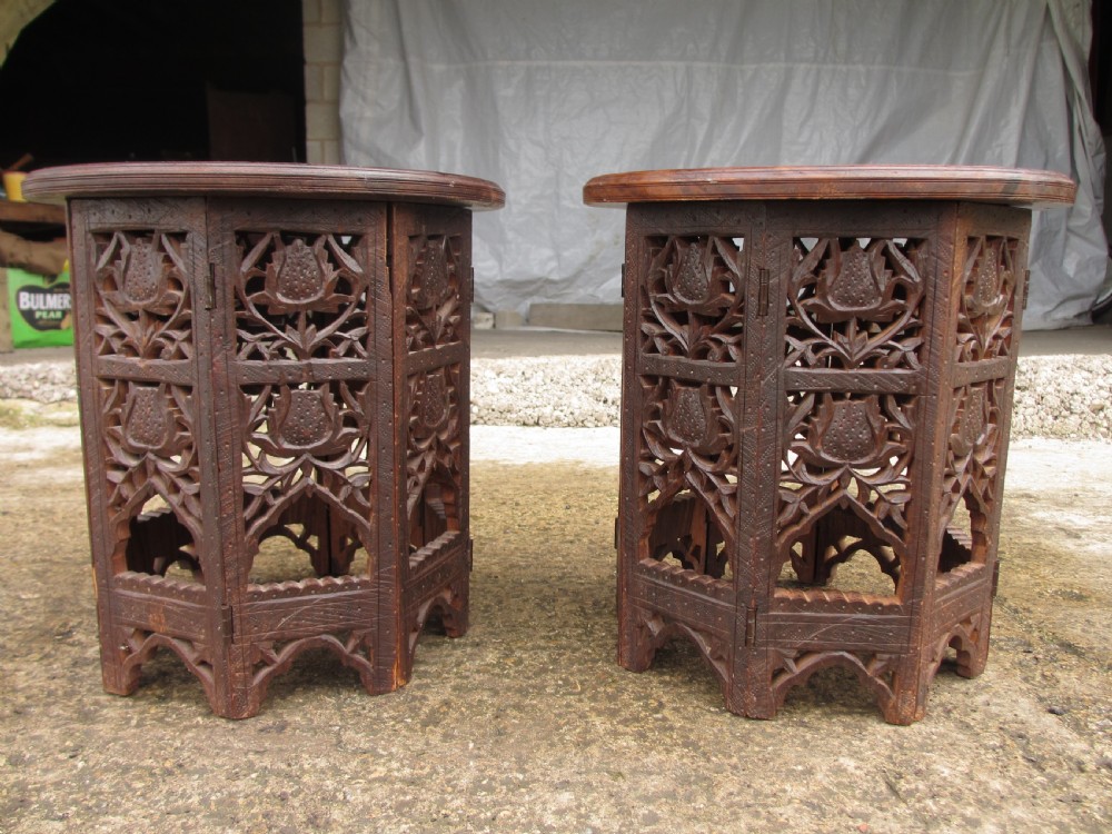 A pair of 19th-century Anglo-Indian padauk wood occasional tables featuring circular tops with deep foliate carvings and central bone inlay set upon collapsible octagonal pierced fretwork bases. View II