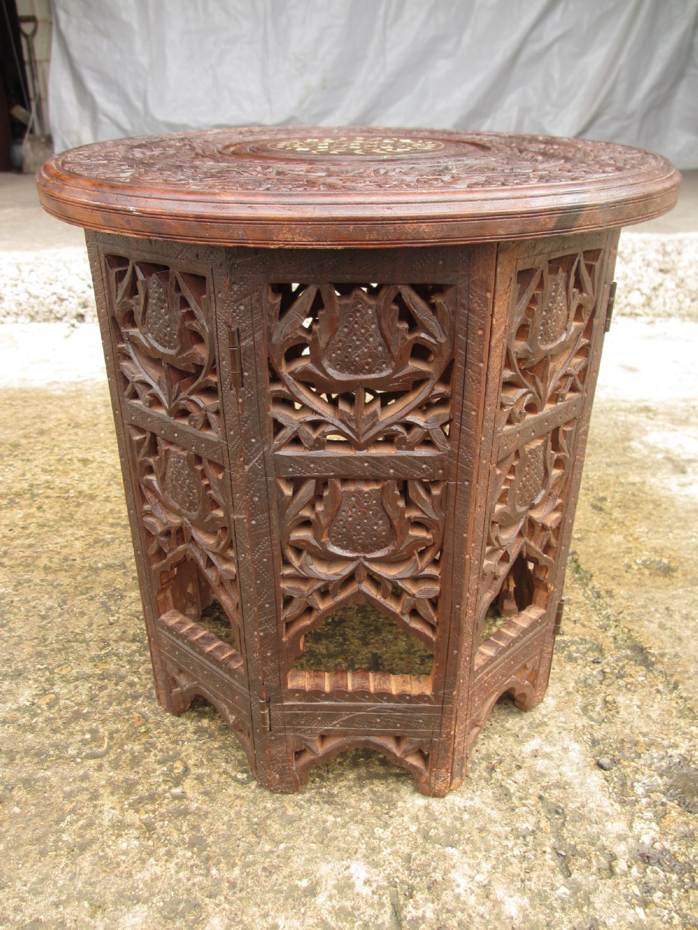 A pair of 19th-century Anglo-Indian padauk wood occasional tables featuring circular tops with deep foliate carvings and central bone inlay set upon collapsible octagonal pierced fretwork bases. View III