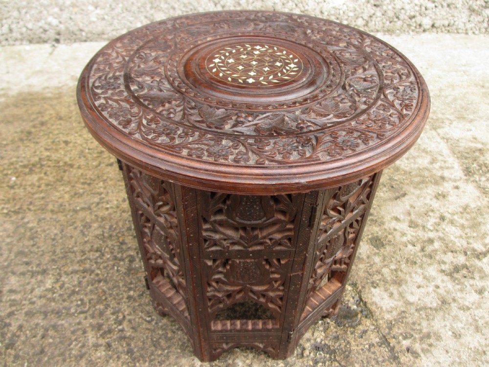 A pair of 19th-century Anglo-Indian padauk wood occasional tables featuring circular tops with deep foliate carvings and central bone inlay set upon collapsible octagonal pierced fretwork bases. View IV