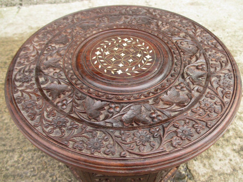 A pair of 19th-century Anglo-Indian padauk wood occasional tables featuring circular tops with deep foliate carvings and central bone inlay set upon collapsible octagonal pierced fretwork bases. View VIII