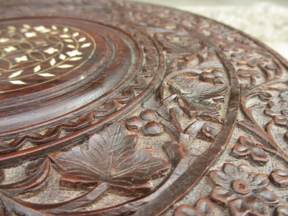 A pair of 19th-century Anglo-Indian padauk wood occasional tables featuring circular tops with deep foliate carvings and central bone inlay set upon collapsible octagonal pierced fretwork bases. View IX