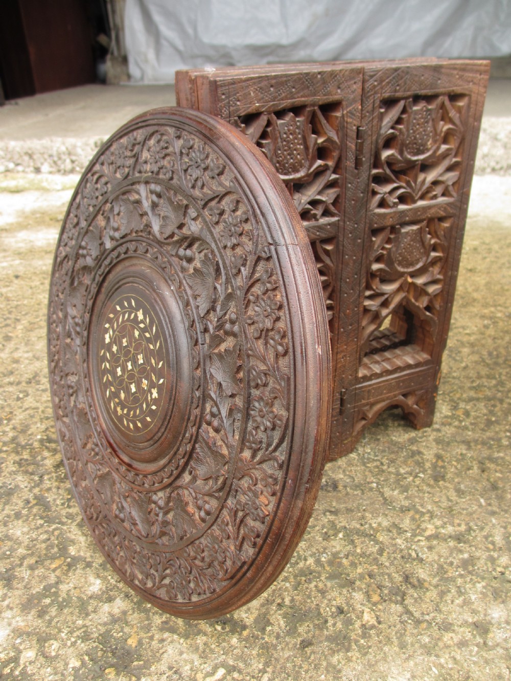 A pair of 19th-century Anglo-Indian padauk wood occasional tables featuring circular tops with deep foliate carvings and central bone inlay set upon collapsible octagonal pierced fretwork bases. View XI