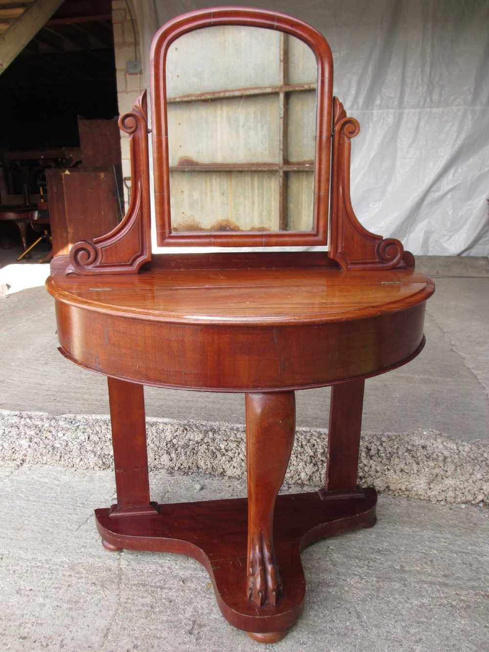 Victorian mahogany demi-lune dressing table featuring an arched swing mirror flanked by scrolled supports and a central carved cabriole front leg.