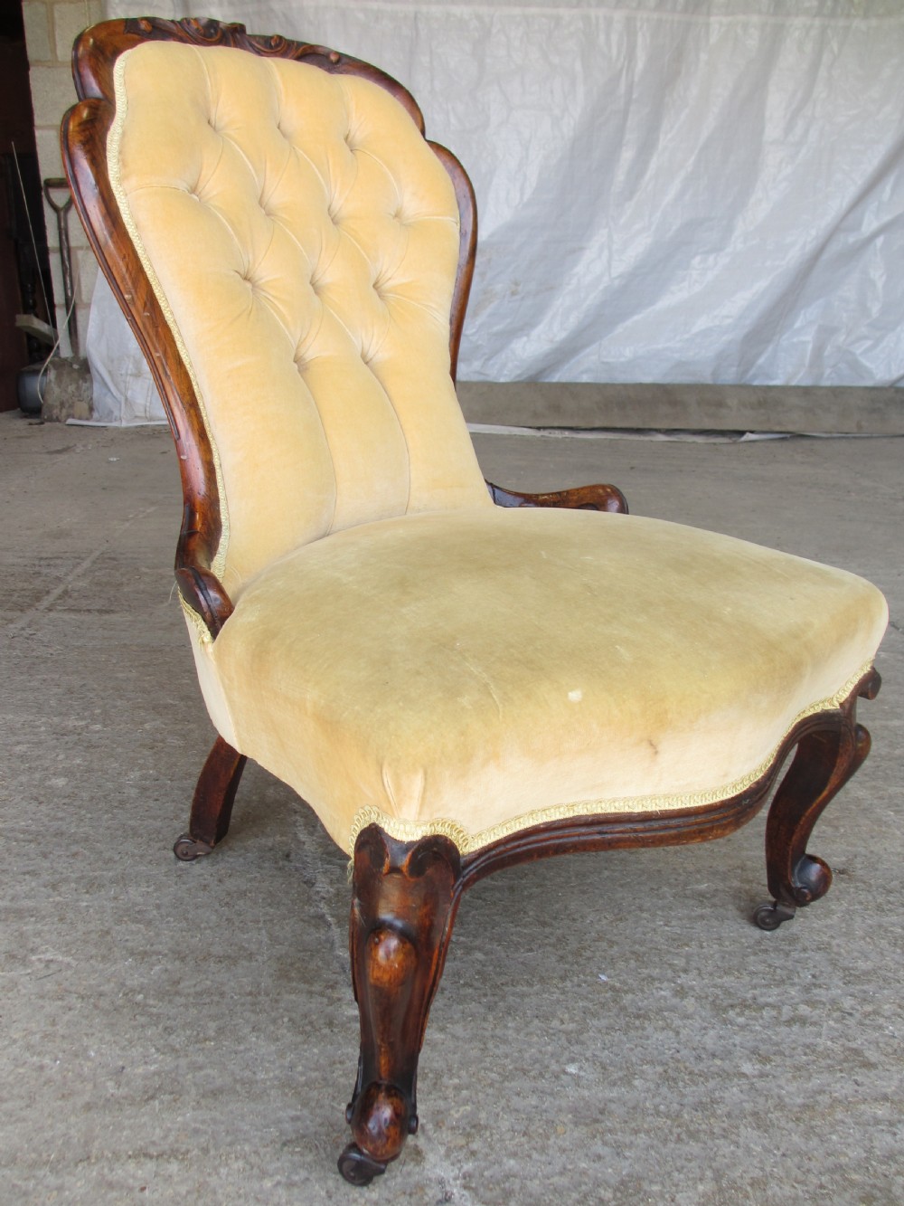 A Victorian spoon back nursing chair featuring yellow velvet button-tufted upholstery and a carved mahogany frame with cabriole legs. View II