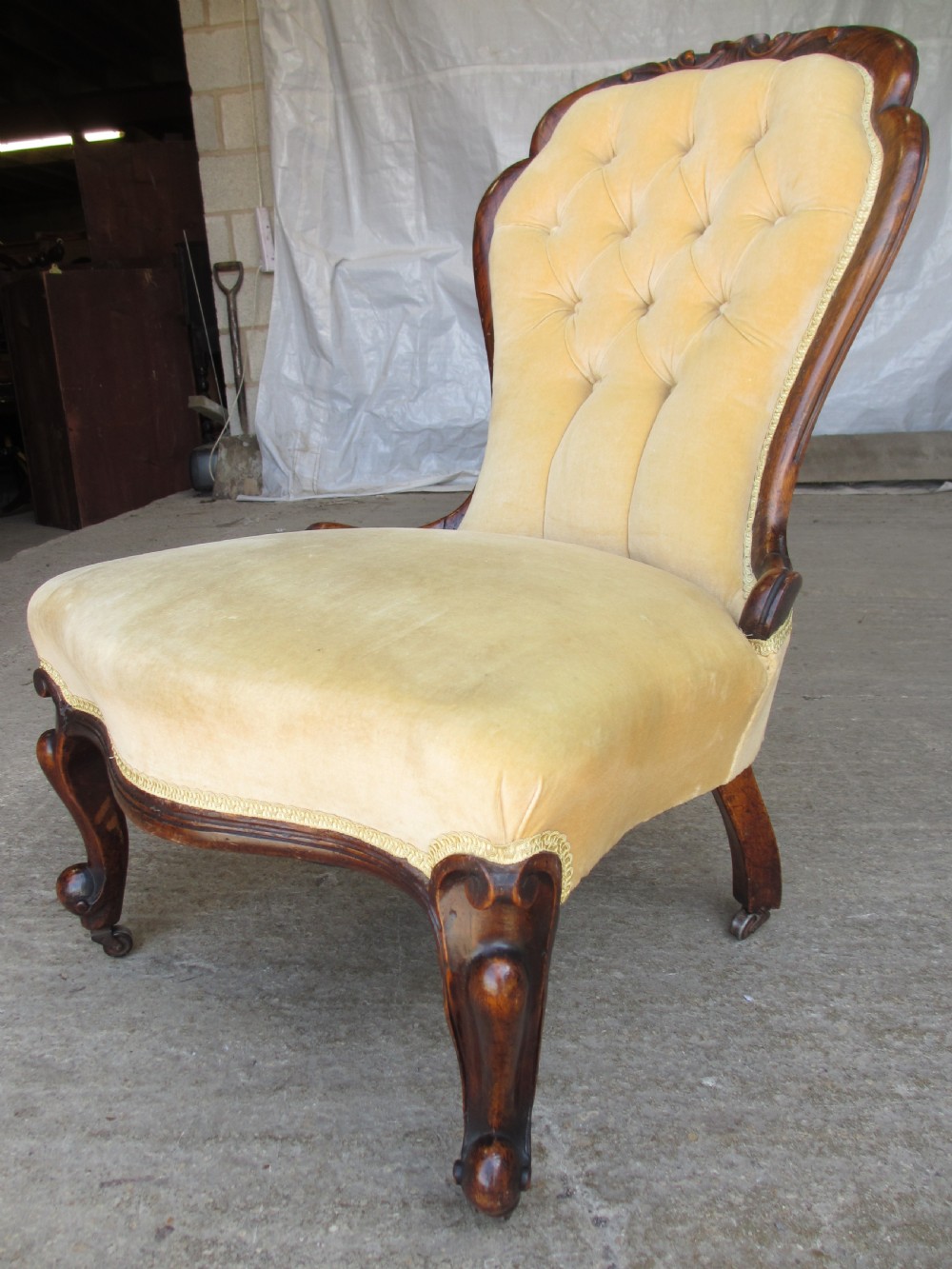 A Victorian spoon back nursing chair featuring yellow velvet button-tufted upholstery and a carved mahogany frame with cabriole legs. View III