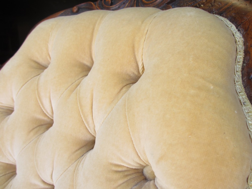 A Victorian spoon back nursing chair featuring yellow velvet button-tufted upholstery and a carved mahogany frame with cabriole legs. View V