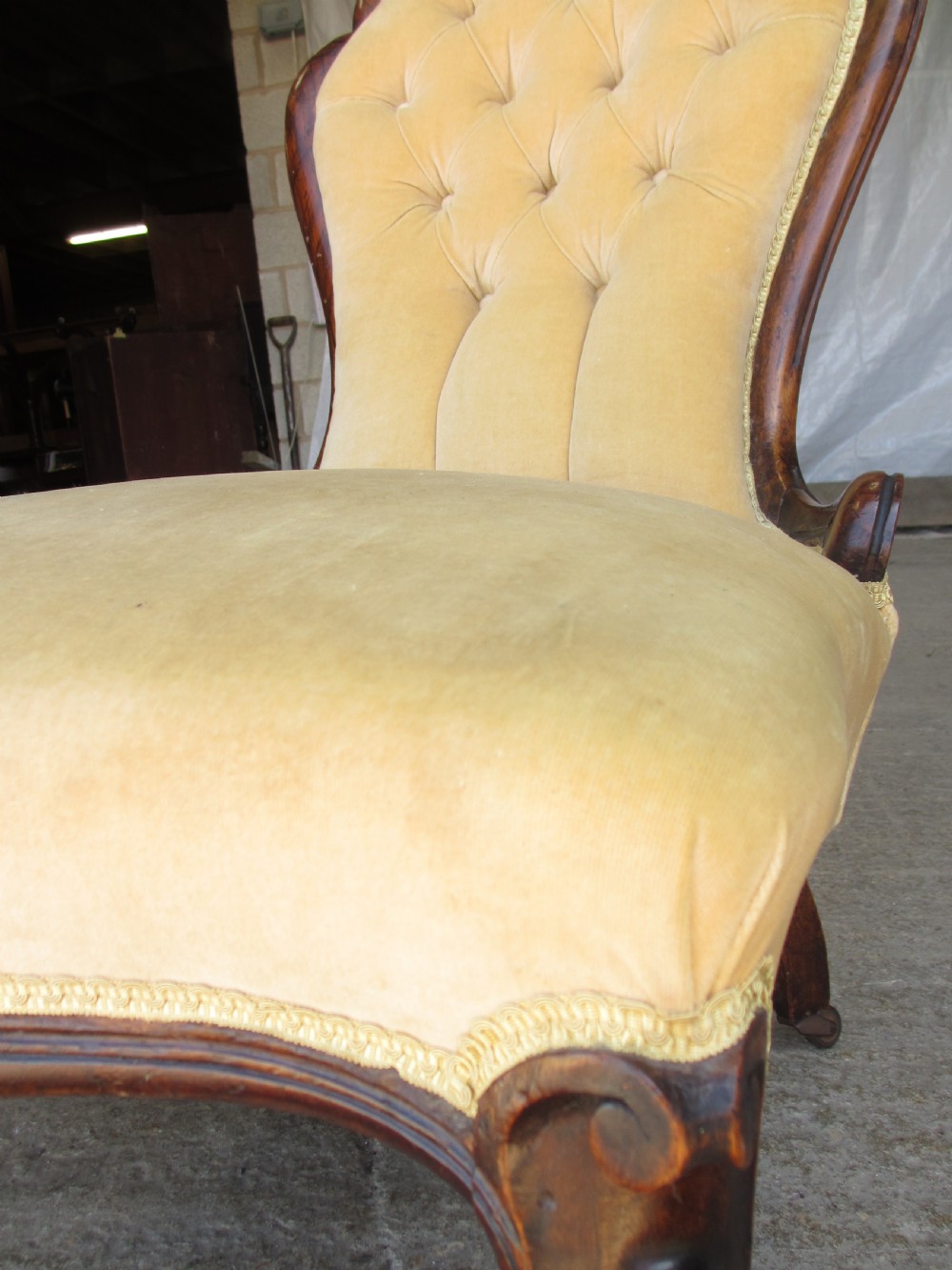 A Victorian spoon back nursing chair featuring yellow velvet button-tufted upholstery and a carved mahogany frame with cabriole legs. View VI