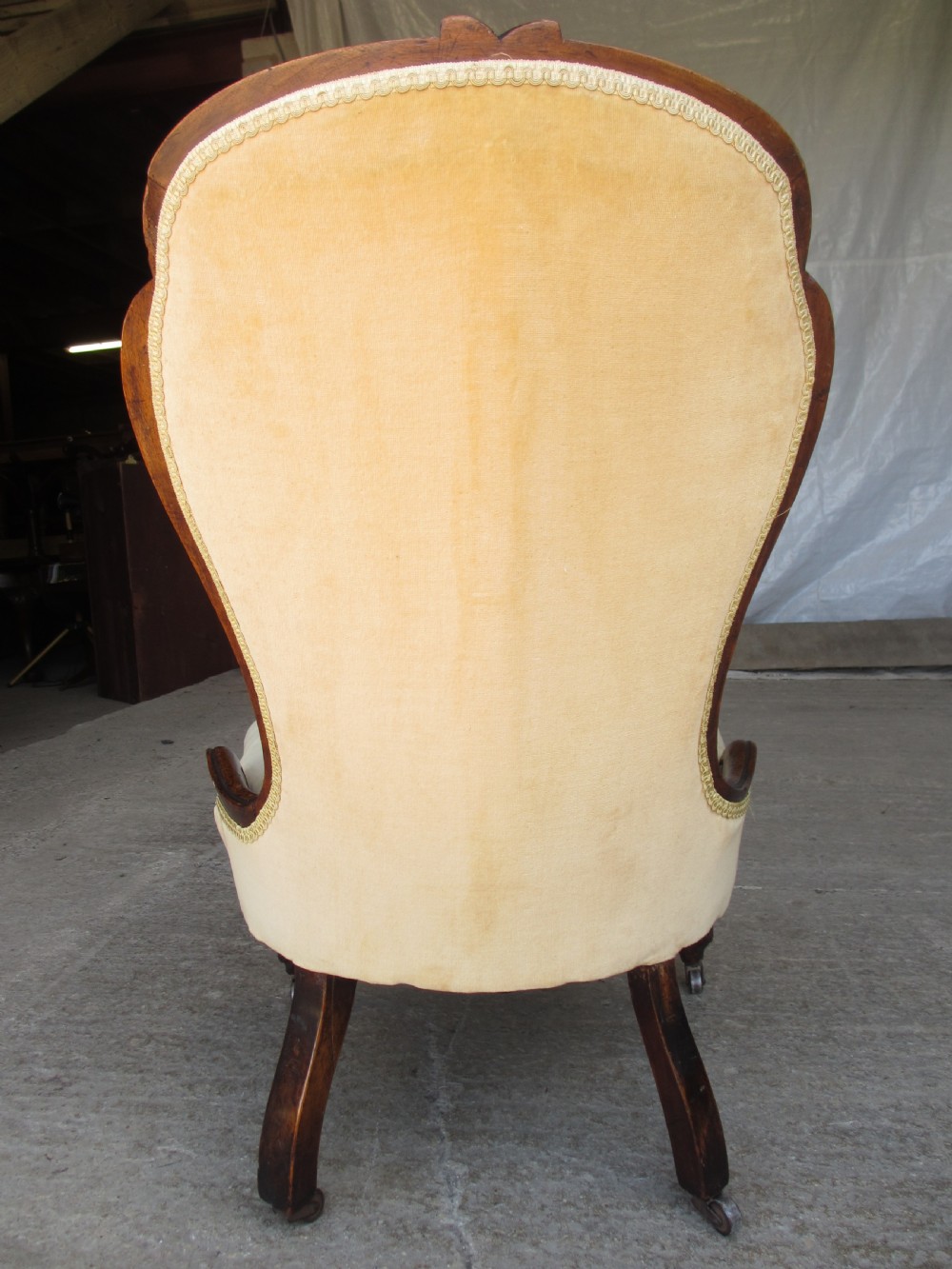 A Victorian spoon back nursing chair featuring yellow velvet button-tufted upholstery and a carved mahogany frame with cabriole legs. View X