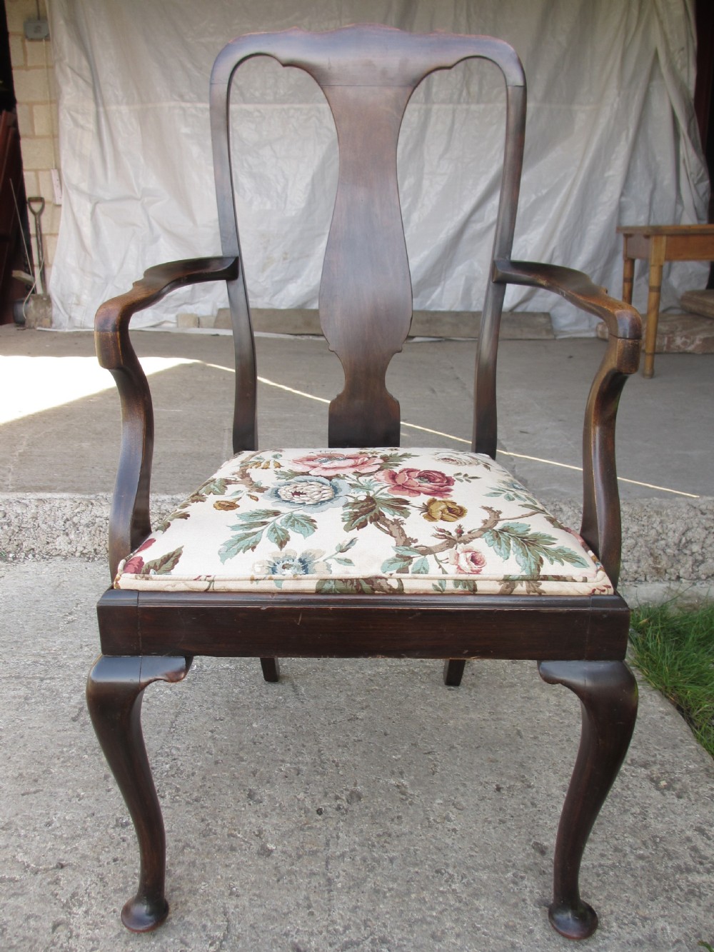 A 19th-century dark mahogany carver armchair featuring a shaped vase back splat, cabriole front legs with pad feet, and a drop-in floral tapestry seat pad.
