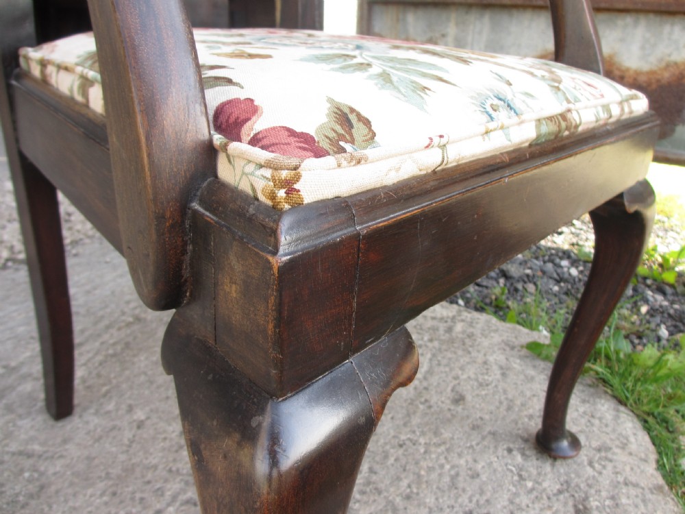 A 19th-century dark mahogany carver armchair featuring a shaped vase back splat, cabriole front legs with pad feet, and a drop-in floral tapestry seat pad. View VI