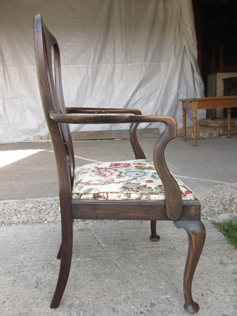 A 19th-century dark mahogany carver armchair featuring a shaped vase back splat, cabriole front legs with pad feet, and a drop-in floral tapestry seat pad. View X
