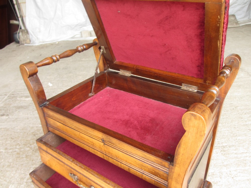 An Edwardian mahogany music stool featuring a red velvet upholstered seat, side turned handles, brass drawer pulls, and cabriole legs. View IX