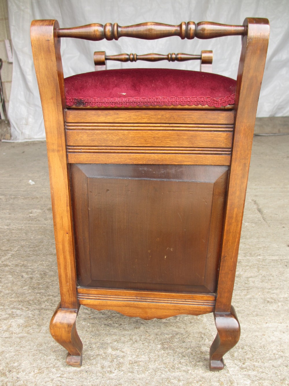 An Edwardian mahogany music stool featuring a red velvet upholstered seat, side turned handles, brass drawer pulls, and cabriole legs. View XI