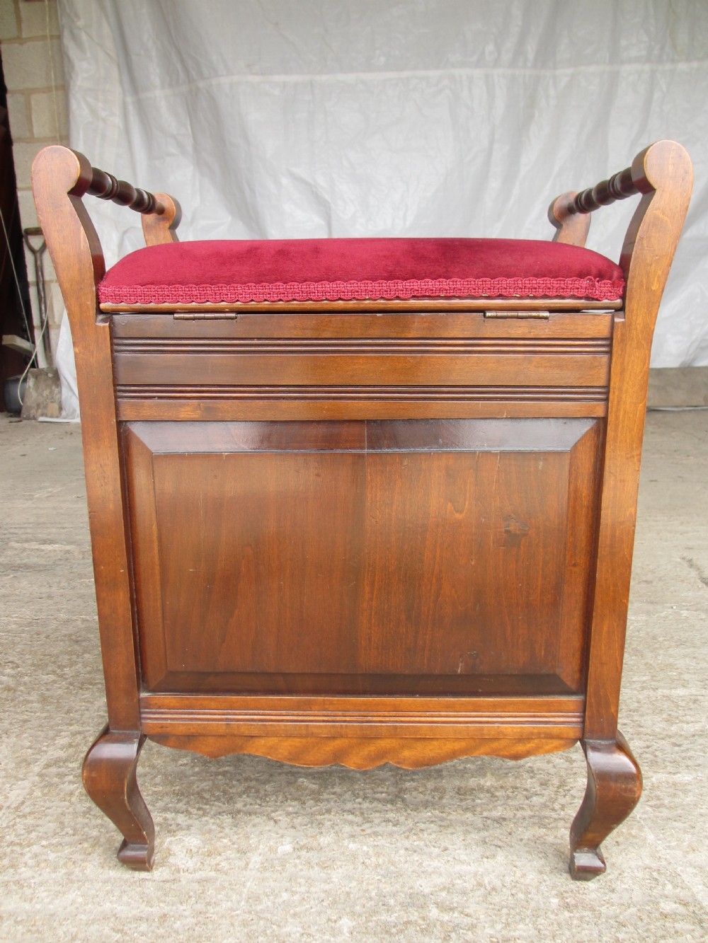 An Edwardian mahogany music stool featuring a red velvet upholstered seat, side turned handles, brass drawer pulls, and cabriole legs. View XII