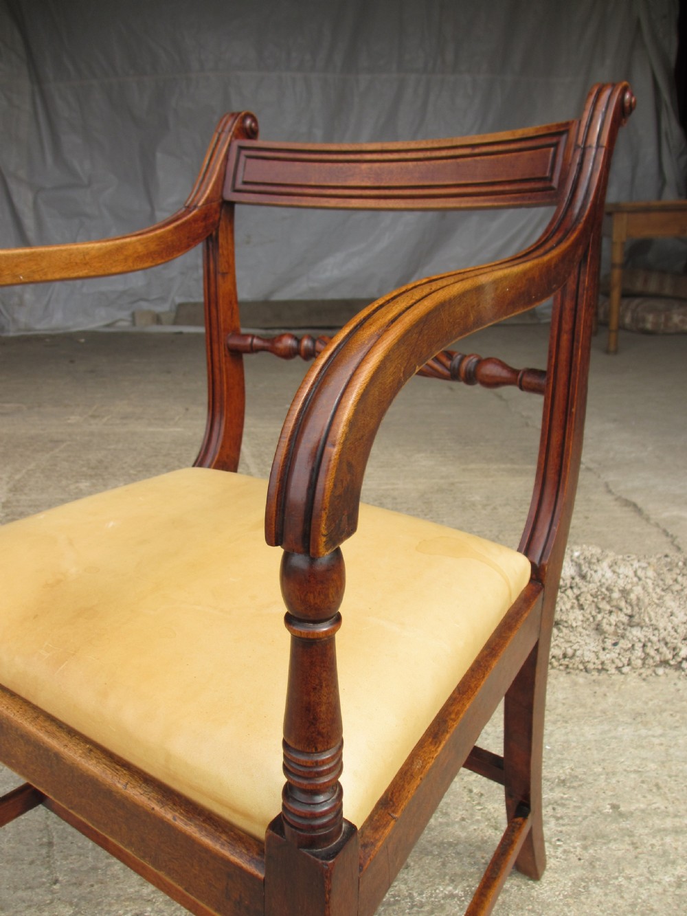 A Georgian mahogany armchair featuring curved reeded arms, a carved rope-twist horizontal back bar, turned front supports, and a tan drop-in upholstered seat. View V