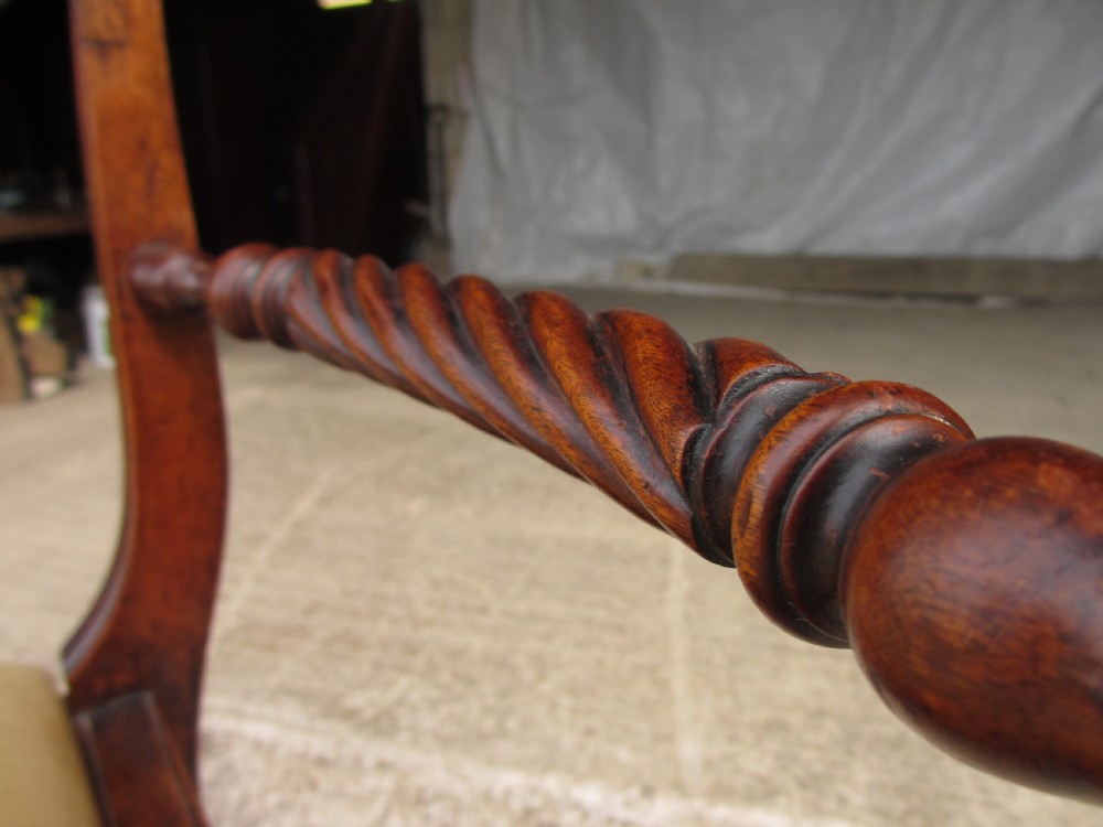 A Georgian mahogany armchair featuring curved reeded arms, a carved rope-twist horizontal back bar, turned front supports, and a tan drop-in upholstered seat. View VI