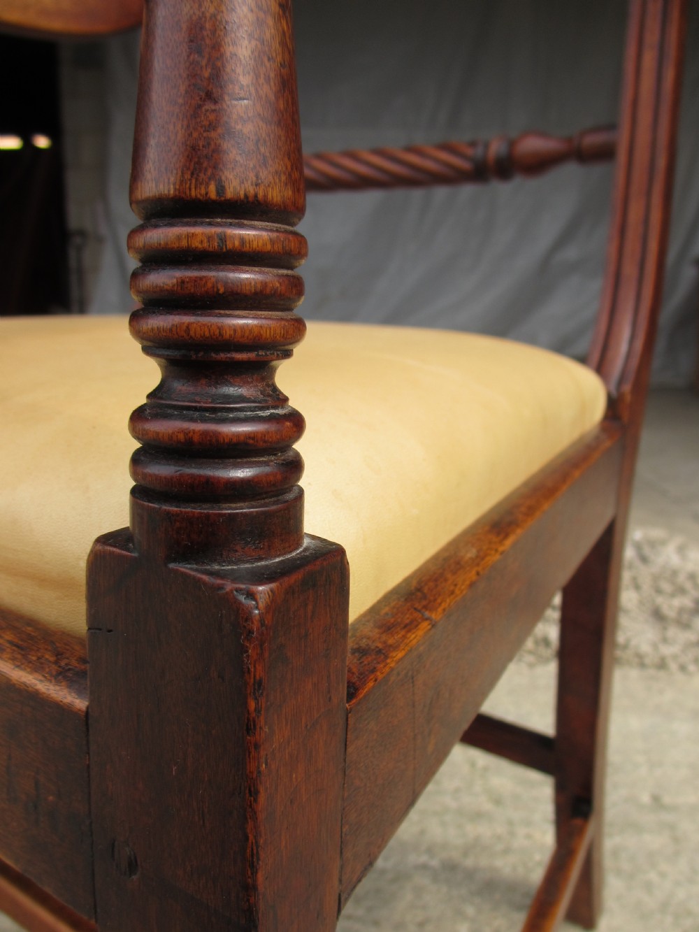 A Georgian mahogany armchair featuring curved reeded arms, a carved rope-twist horizontal back bar, turned front supports, and a tan drop-in upholstered seat. View IX