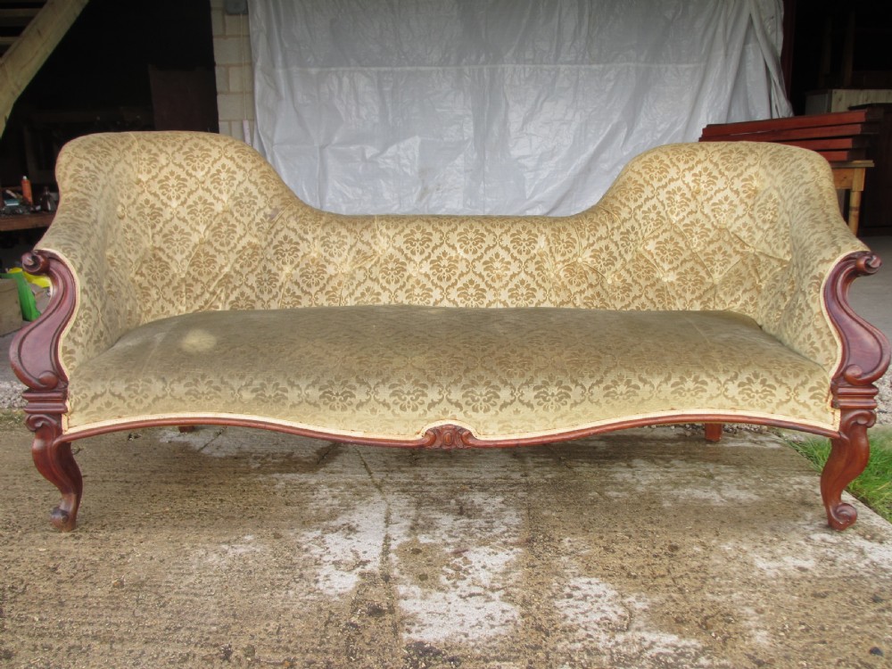An early Victorian mahogany showood sofa with button-tufted gold damask upholstery and carved cabriole legs.