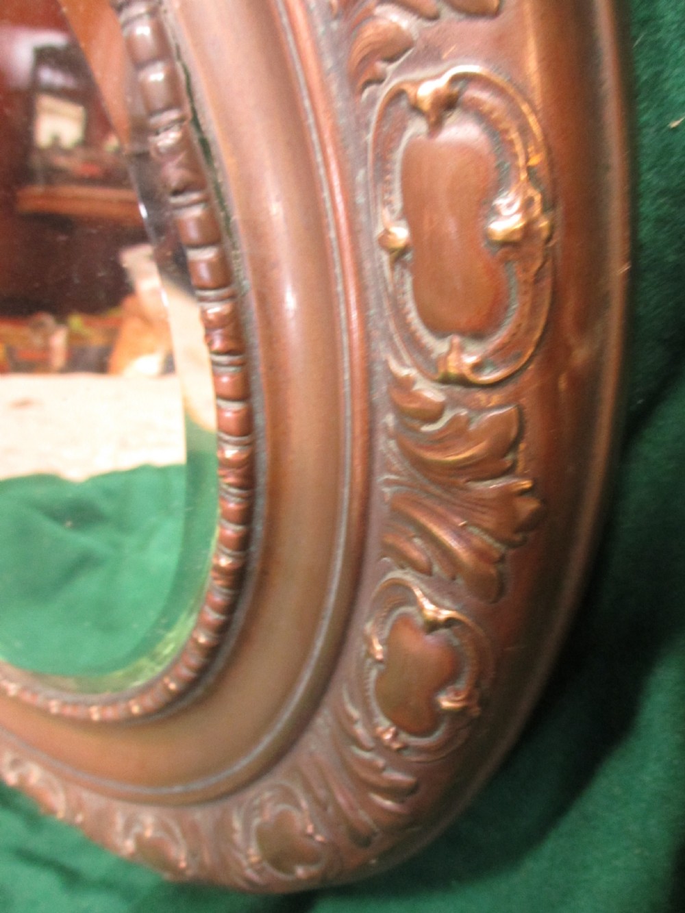 A circular Victorian brass wall mirror featuring an embossed floral patterned frame and a bevelled glass mirror plate. View VIII