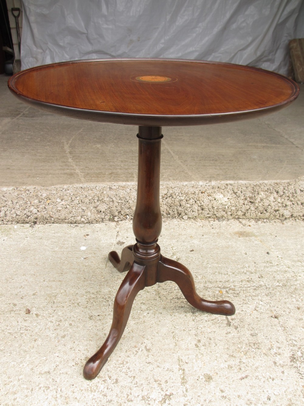 A circular Georgian mahogany tripod table featuring a central inlaid satinwood rosette, turned pedestal stem, and three curved legs.
