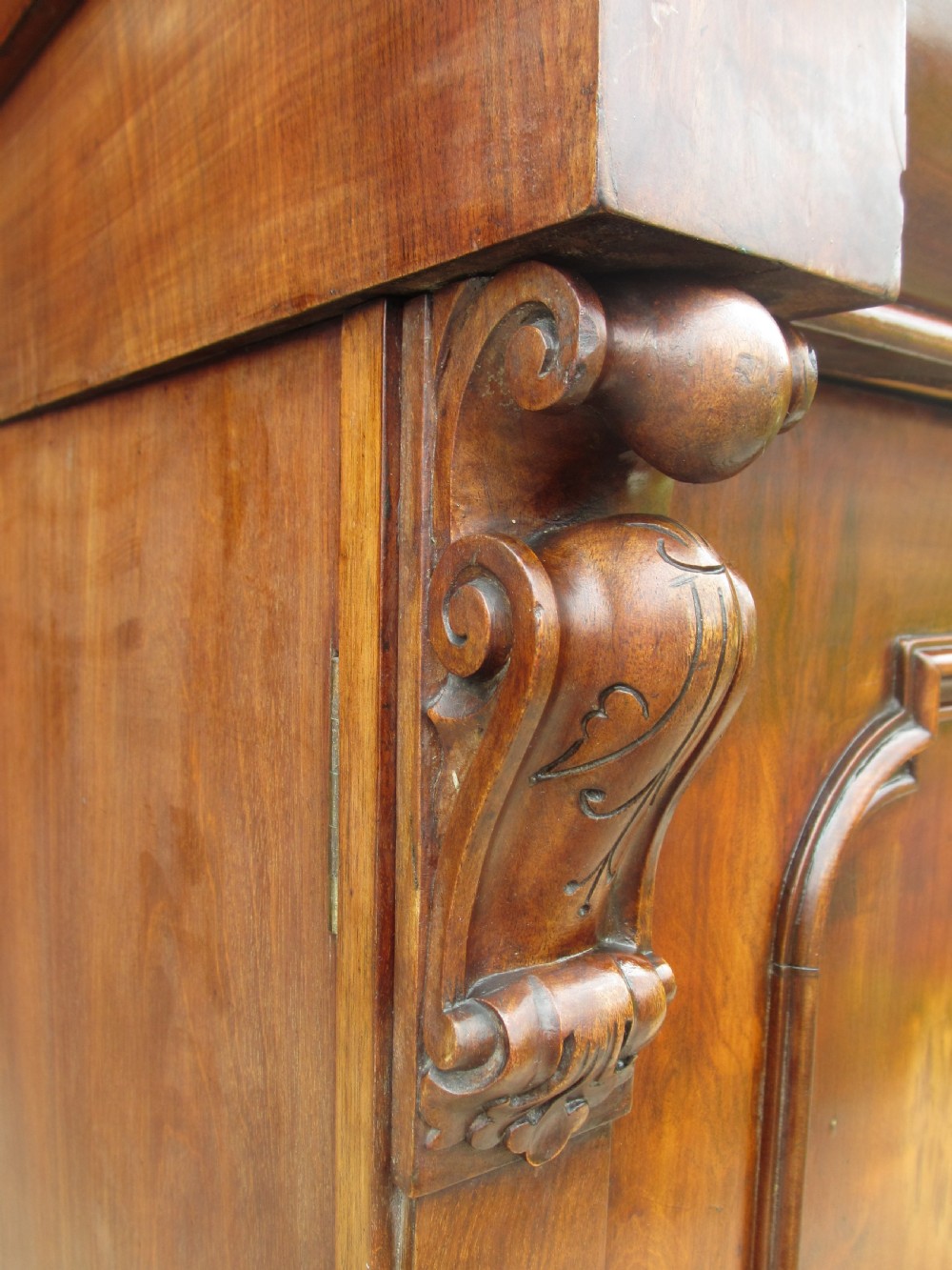 A Victorian mahogany chiffonier featuring two lower cupboard doors with figured plum pudding veneer panels, topped with two open display shelves supported by carved scroll brackets and a fretwork cresting. View VIII