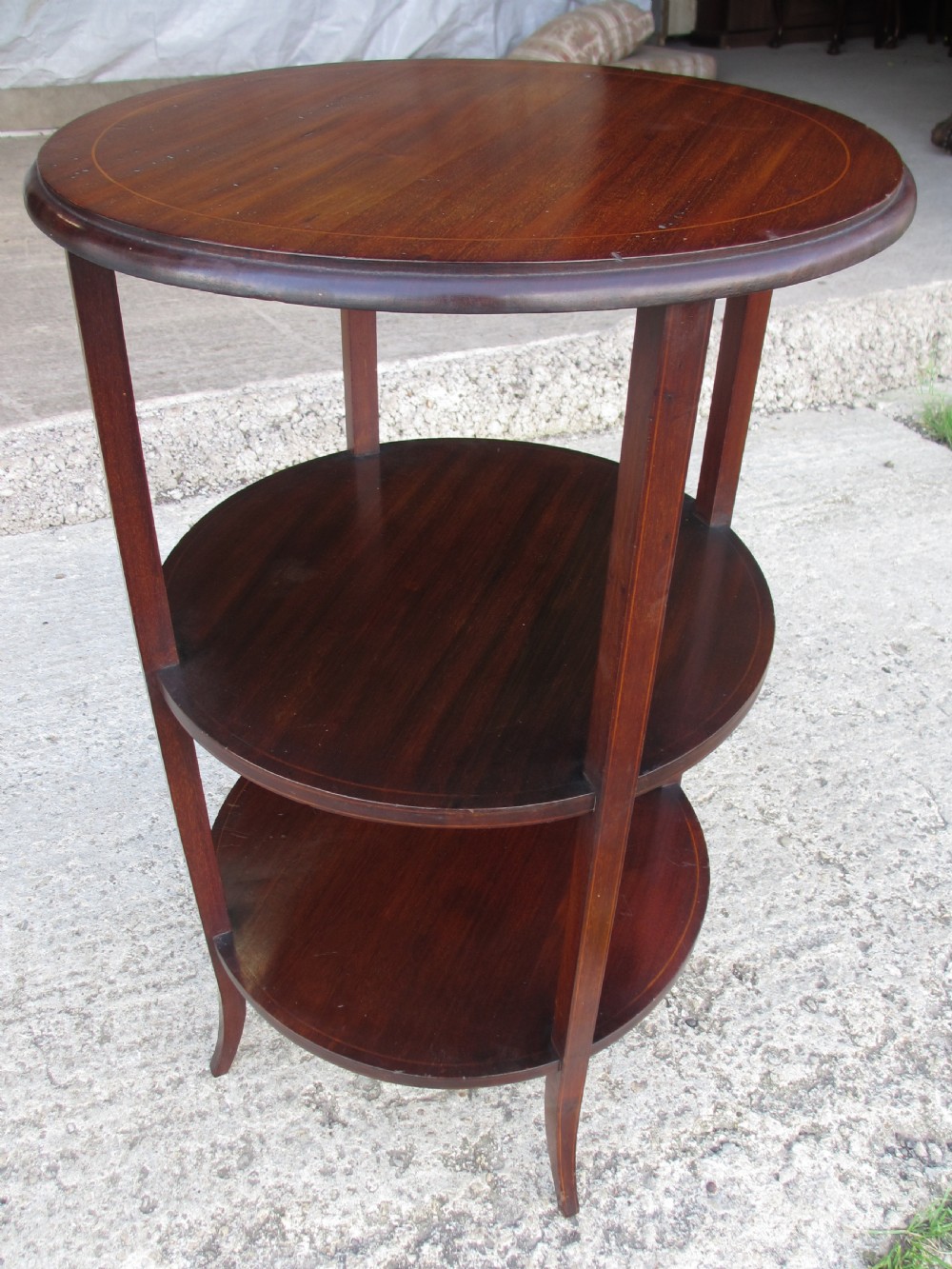 An Edwardian circular dark mahogany etagere featuring three tiers supported by four slender legs with inlaid edge detailing. View II