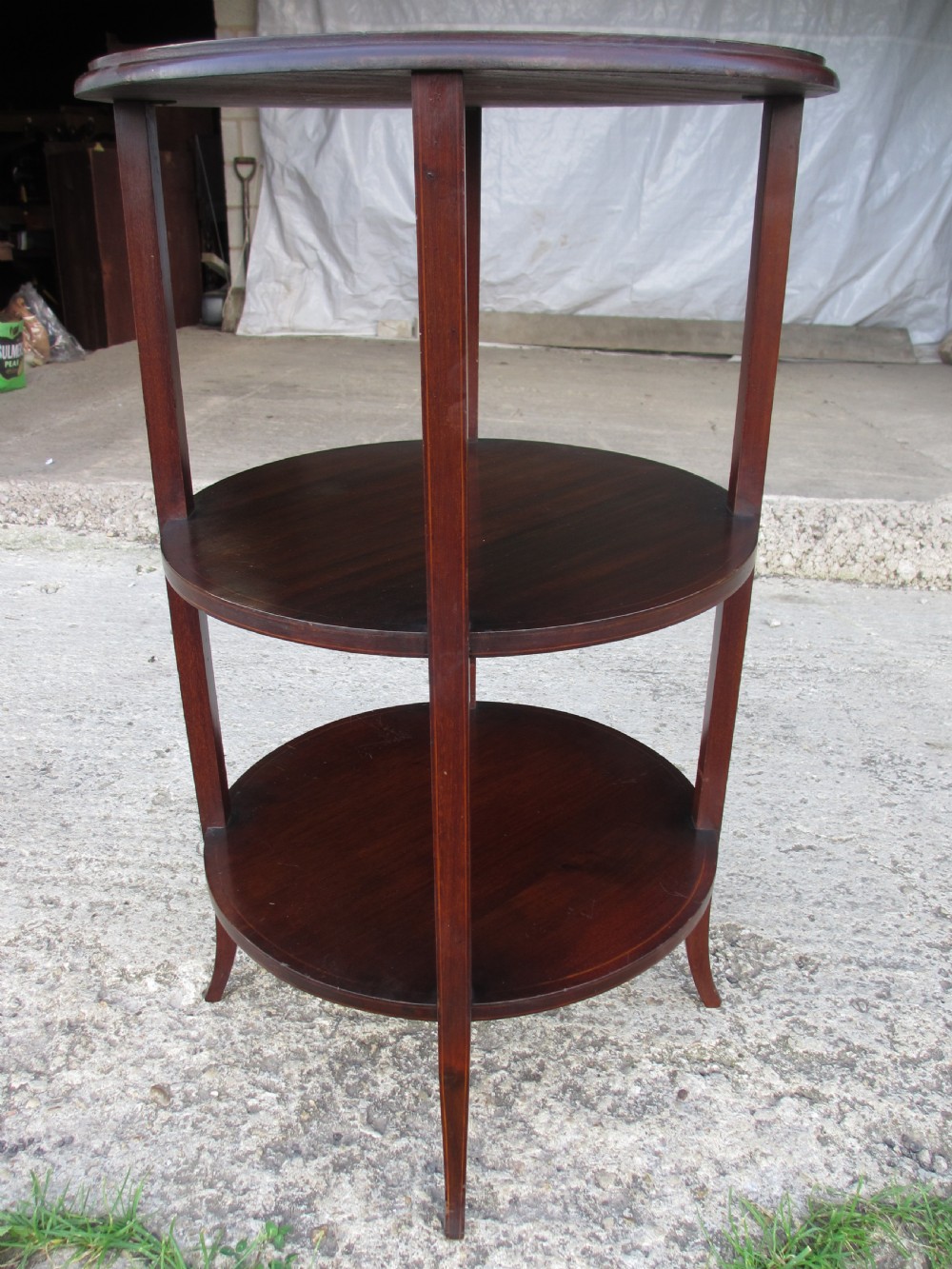 An Edwardian circular dark mahogany etagere featuring three tiers supported by four slender legs with inlaid edge detailing.