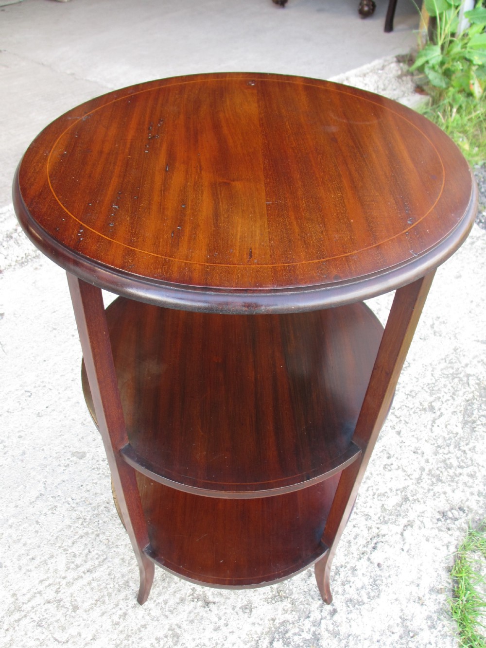 An Edwardian circular dark mahogany etagere featuring three tiers supported by four slender legs with inlaid edge detailing. View IV