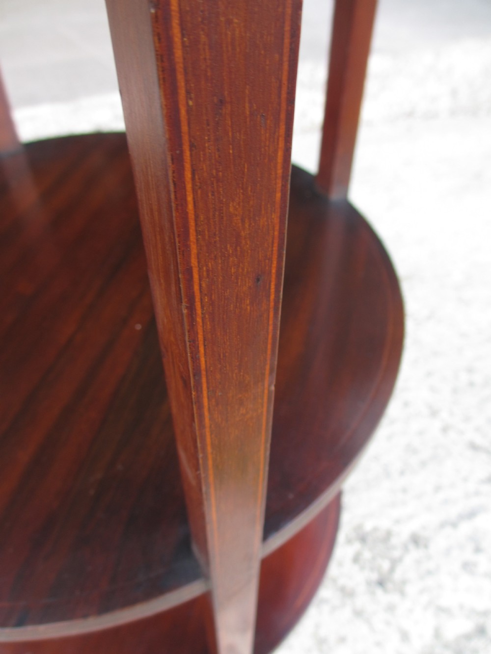An Edwardian circular dark mahogany etagere featuring three tiers supported by four slender legs with inlaid edge detailing. View VI