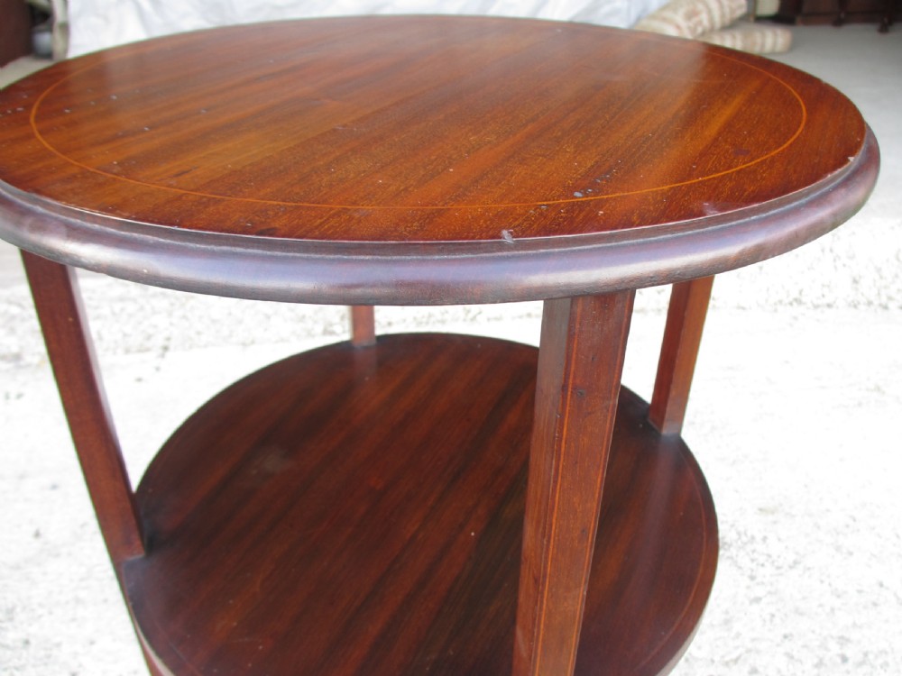 An Edwardian circular dark mahogany etagere featuring three tiers supported by four slender legs with inlaid edge detailing. View VII