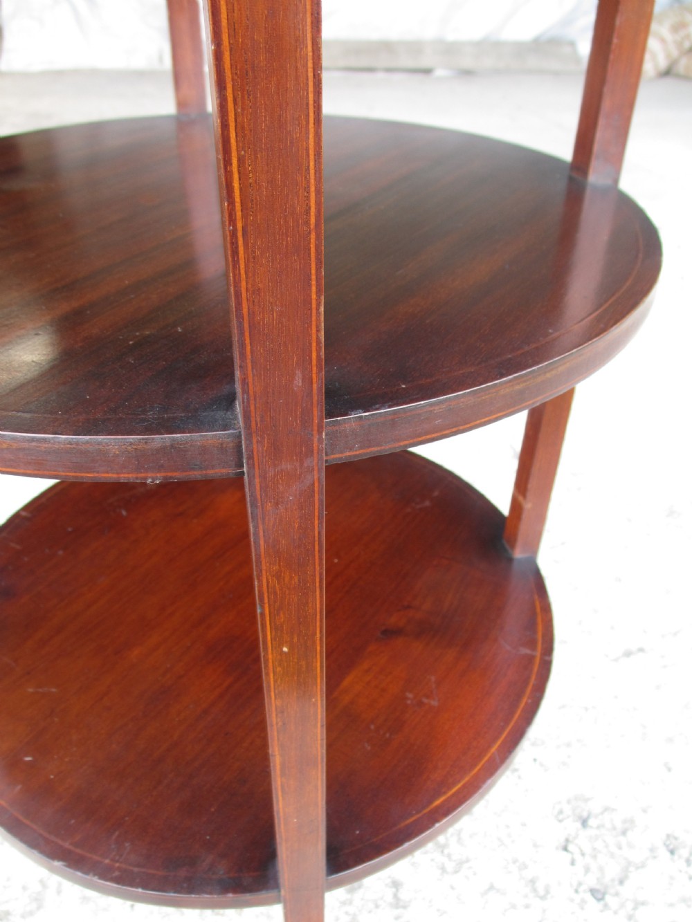 An Edwardian circular dark mahogany etagere featuring three tiers supported by four slender legs with inlaid edge detailing. View VIII
