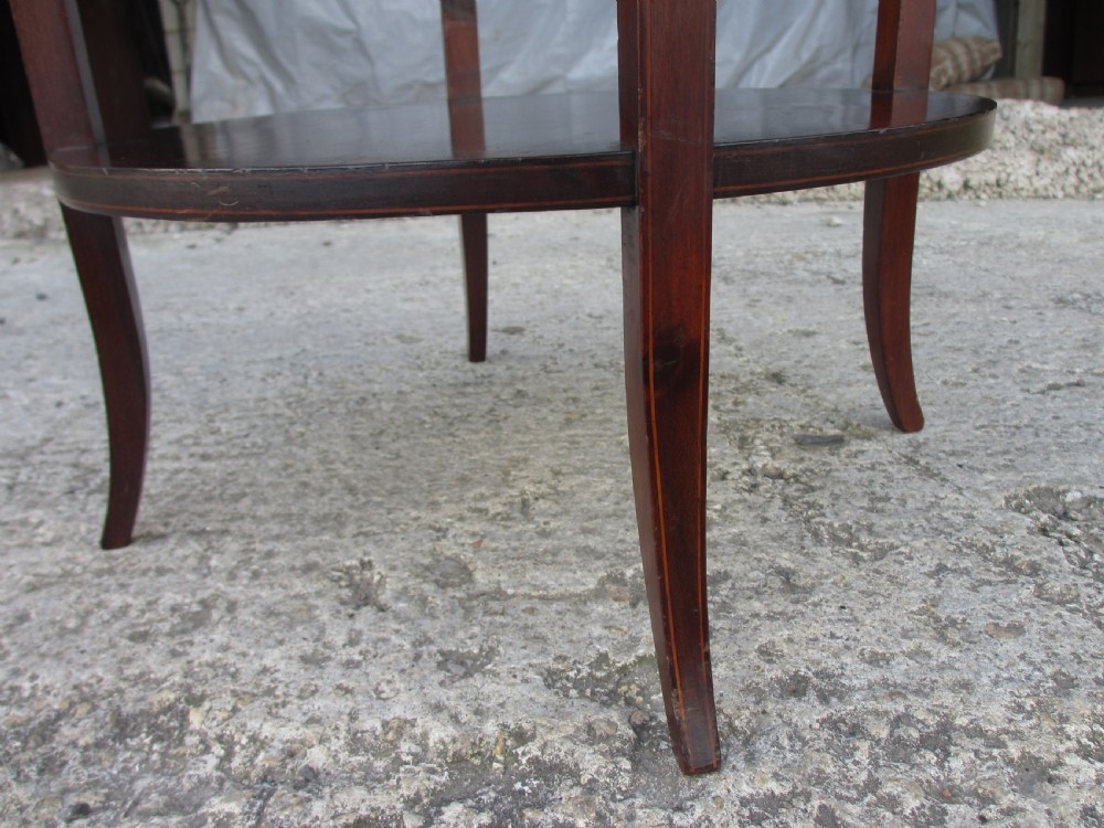An Edwardian circular dark mahogany etagere featuring three tiers supported by four slender legs with inlaid edge detailing. View IX