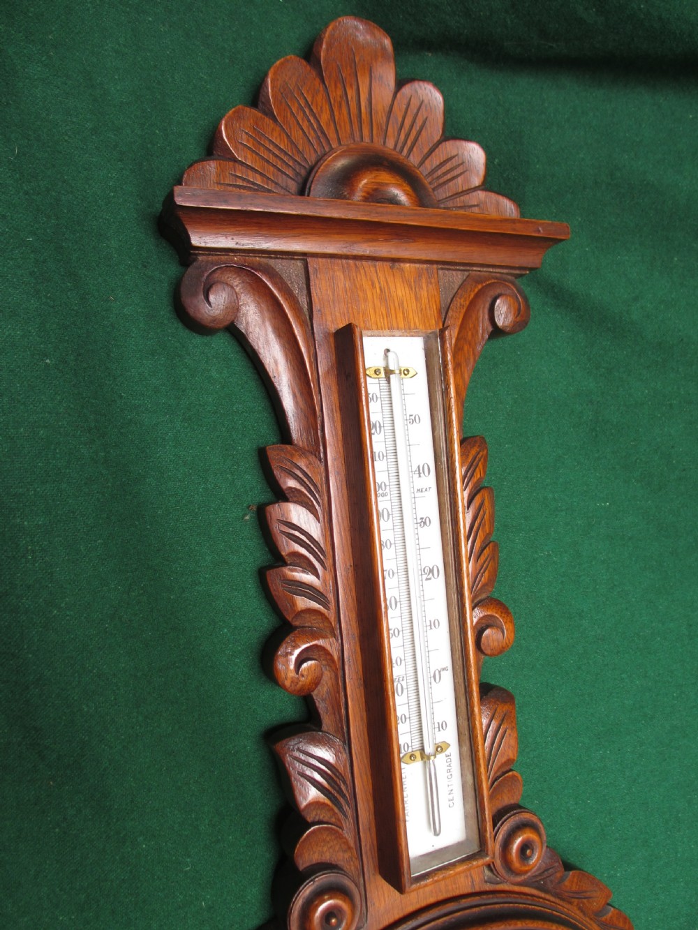 A Victorian carved oak wall barometer featuring an upper thermometer, intricate leaf scrollwork motifs, and a circular white dial with a brass bezel. View IV