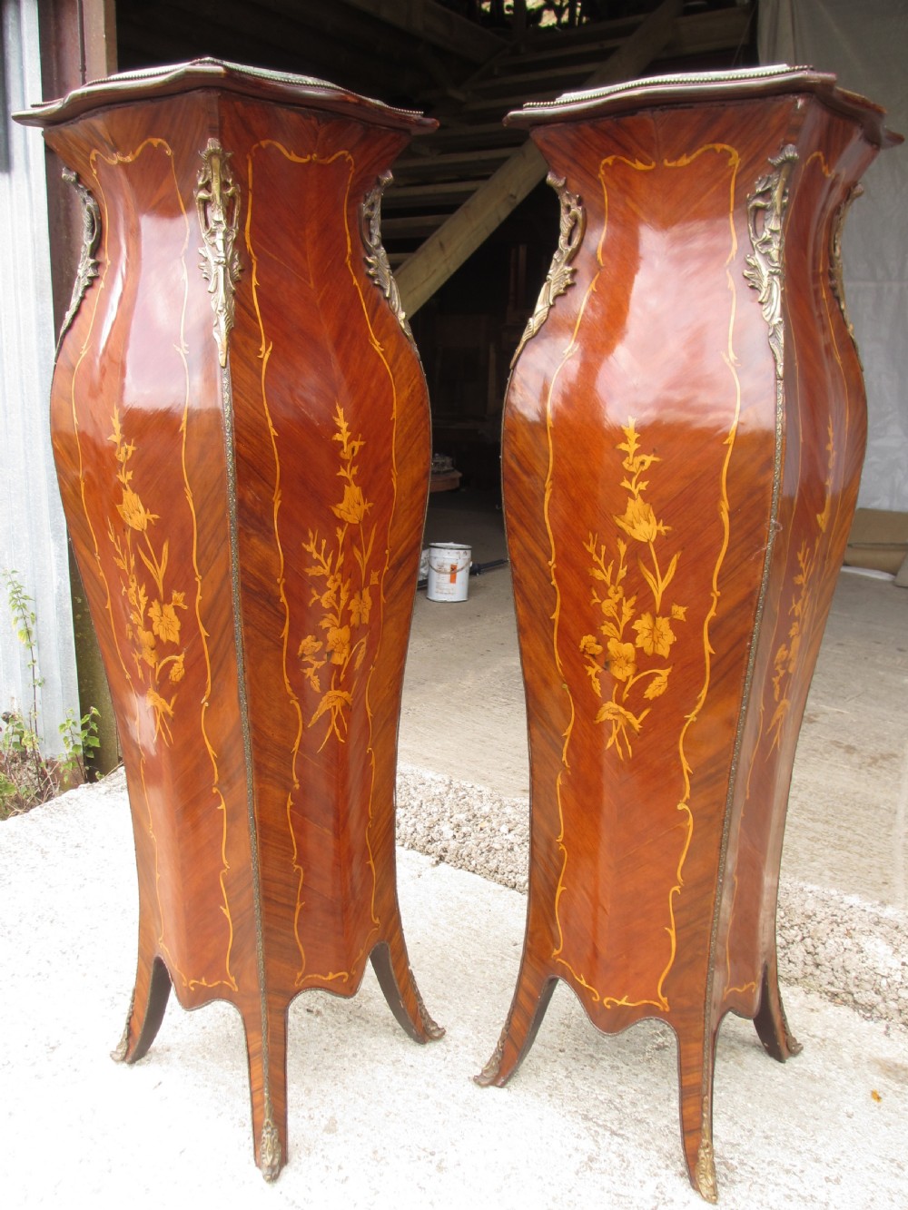 A pair of tall French Louis XV style wooden pedestals featuring floral marquetry inlays, curved silhouettes, and decorative gilt-bronze mounts. View IV