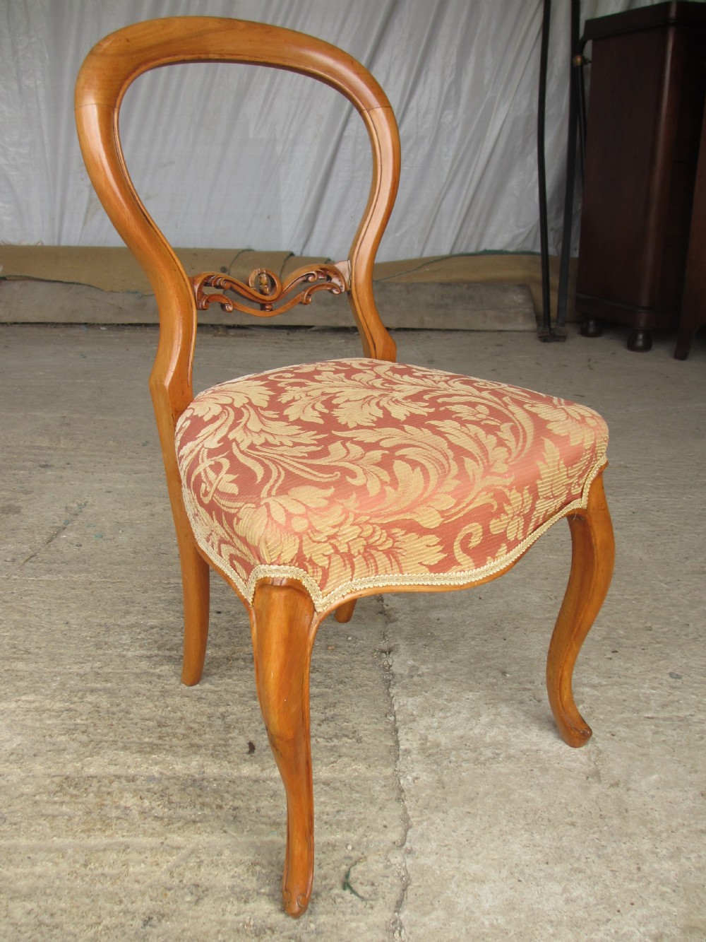 A set of three Victorian mahogany dining chairs featuring rounded balloon backs, carved central splats, cabriole front legs, and terracotta floral upholstery. View III