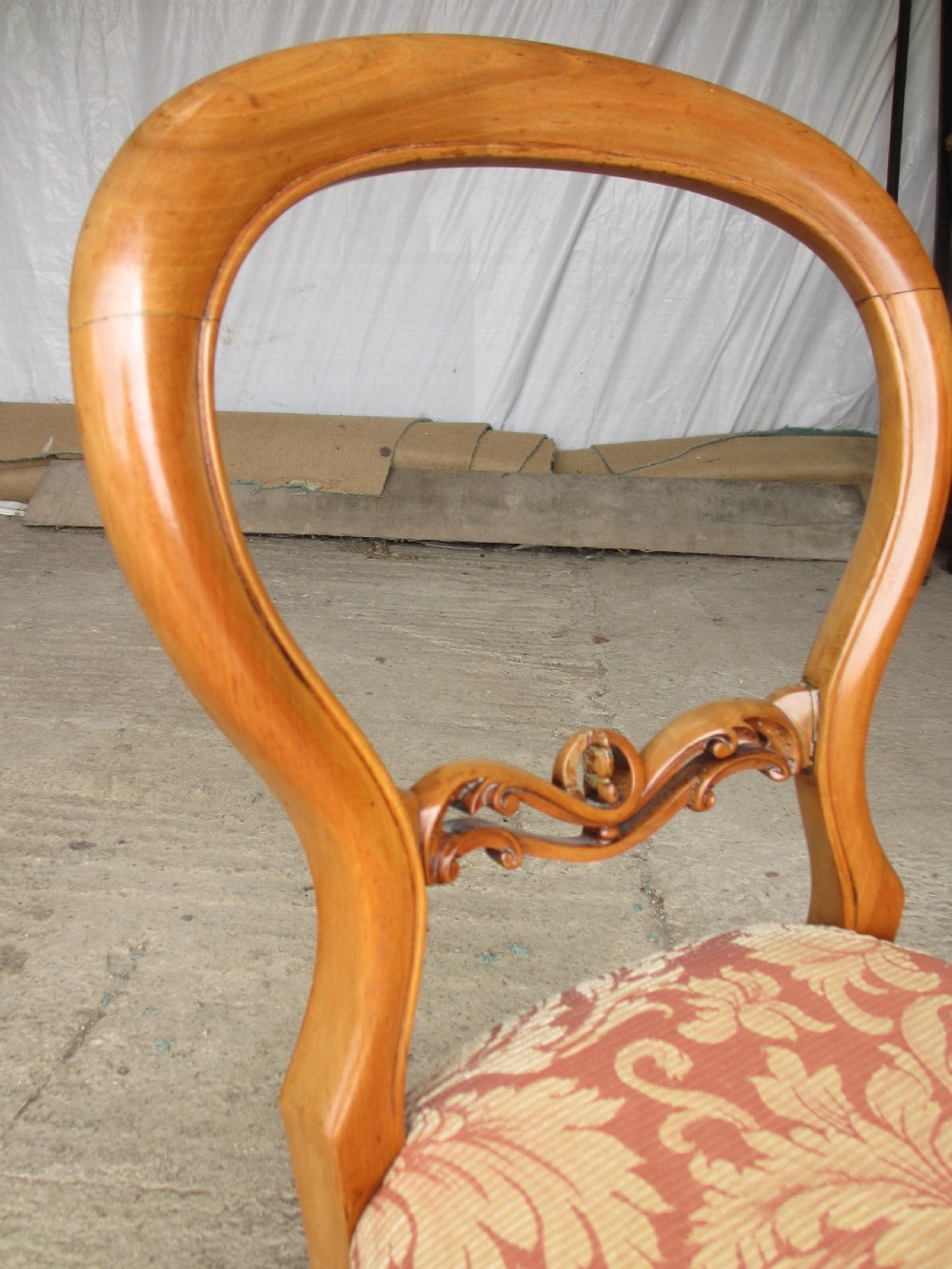 A set of three Victorian mahogany dining chairs featuring rounded balloon backs, carved central splats, cabriole front legs, and terracotta floral upholstery. View IV