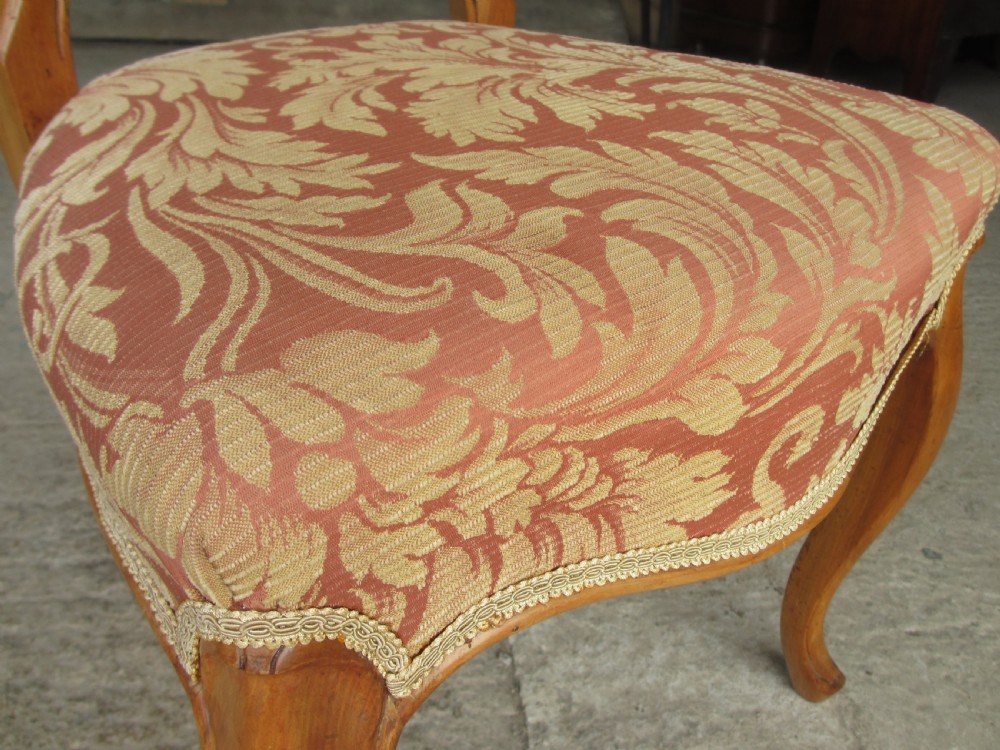 A set of three Victorian mahogany dining chairs featuring rounded balloon backs, carved central splats, cabriole front legs, and terracotta floral upholstery. View VI