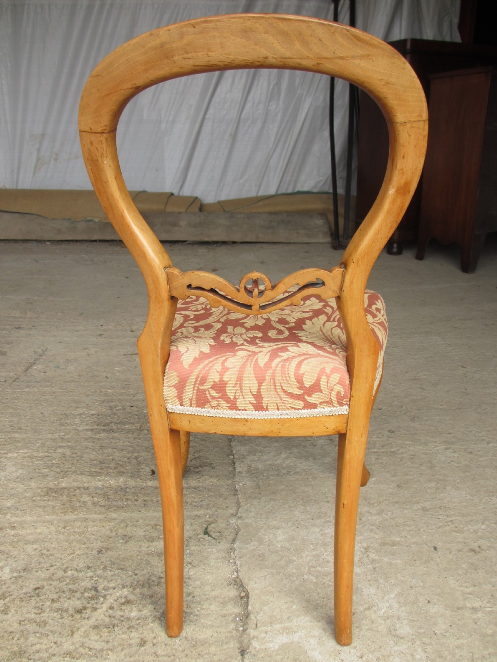 A set of three Victorian mahogany dining chairs featuring rounded balloon backs, carved central splats, cabriole front legs, and terracotta floral upholstery. View X