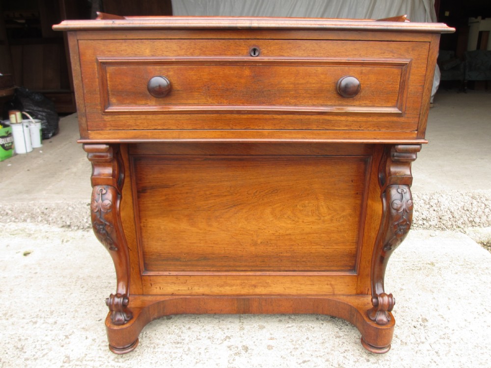 A Victorian rosewood davenport secretaire desk featuring an open black leather-lined writing slope, an upper gallery with drawers and pigeonholes, side drawers, and carved cabriole supports. View II