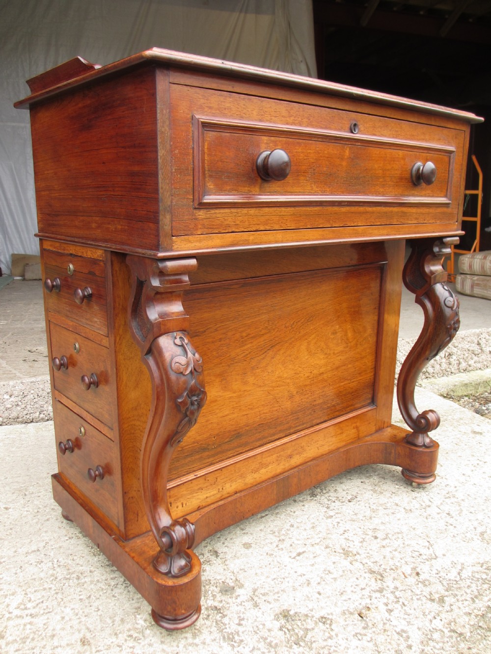 A Victorian rosewood davenport secretaire desk featuring an open black leather-lined writing slope, an upper gallery with drawers and pigeonholes, side drawers, and carved cabriole supports. View III