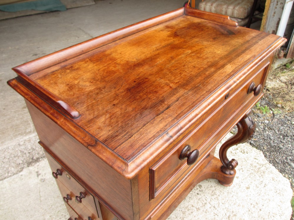 A Victorian rosewood davenport secretaire desk featuring an open black leather-lined writing slope, an upper gallery with drawers and pigeonholes, side drawers, and carved cabriole supports. View V