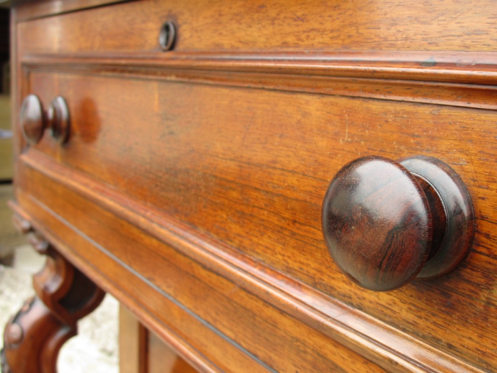 A Victorian rosewood davenport secretaire desk featuring an open black leather-lined writing slope, an upper gallery with drawers and pigeonholes, side drawers, and carved cabriole supports. View VI