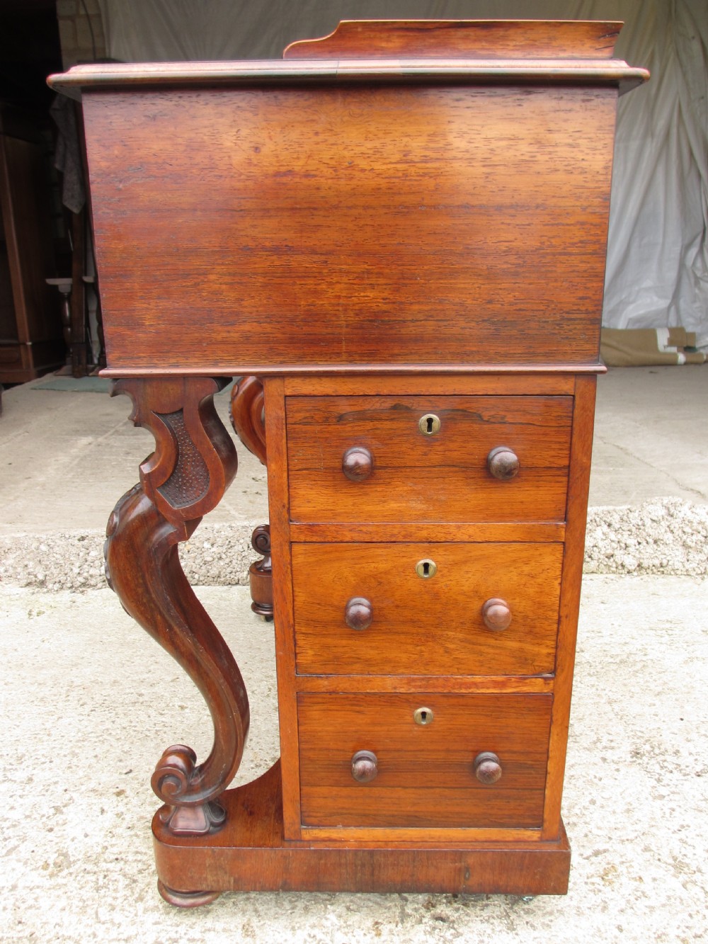 A Victorian rosewood davenport secretaire desk featuring an open black leather-lined writing slope, an upper gallery with drawers and pigeonholes, side drawers, and carved cabriole supports. View XI