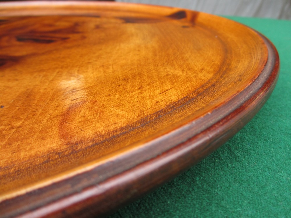 A circular turned mahogany wooden tray featuring a central branded portrait of a laughing jester wearing a cap with bells. View IX