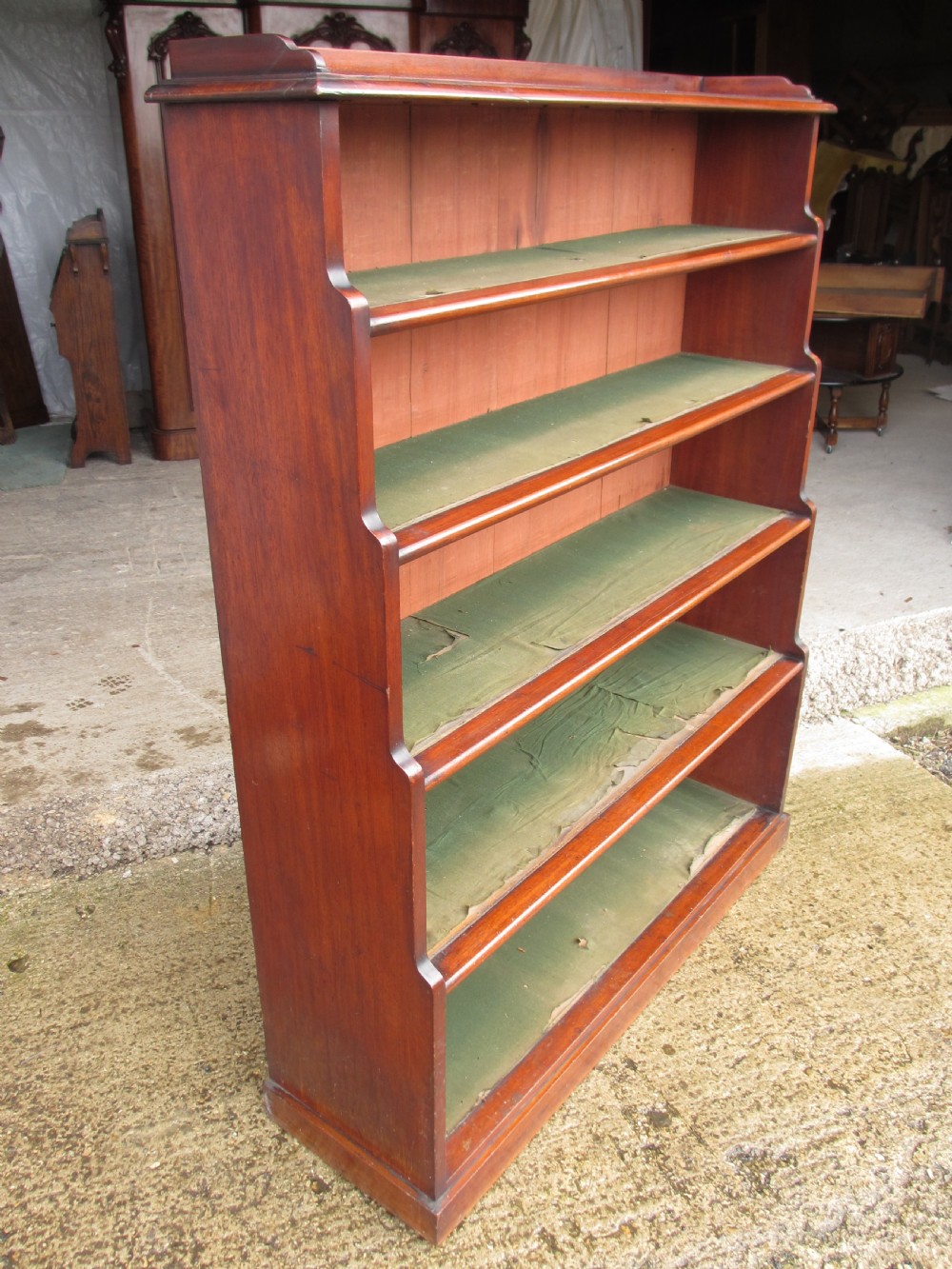 A tall 19th-century mahogany waterfall bookcase featuring six graduating open shelves with green fabric lining and a shaped gallery top. View V