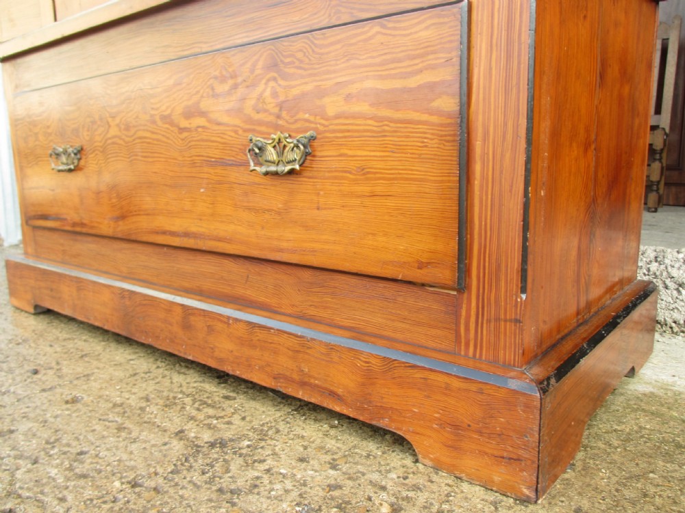A Victorian pitch pine freestanding wardrobe featuring a central bevelled mirror door, upper spindle gallery, panelled sides, and a single lower drawer. View VII