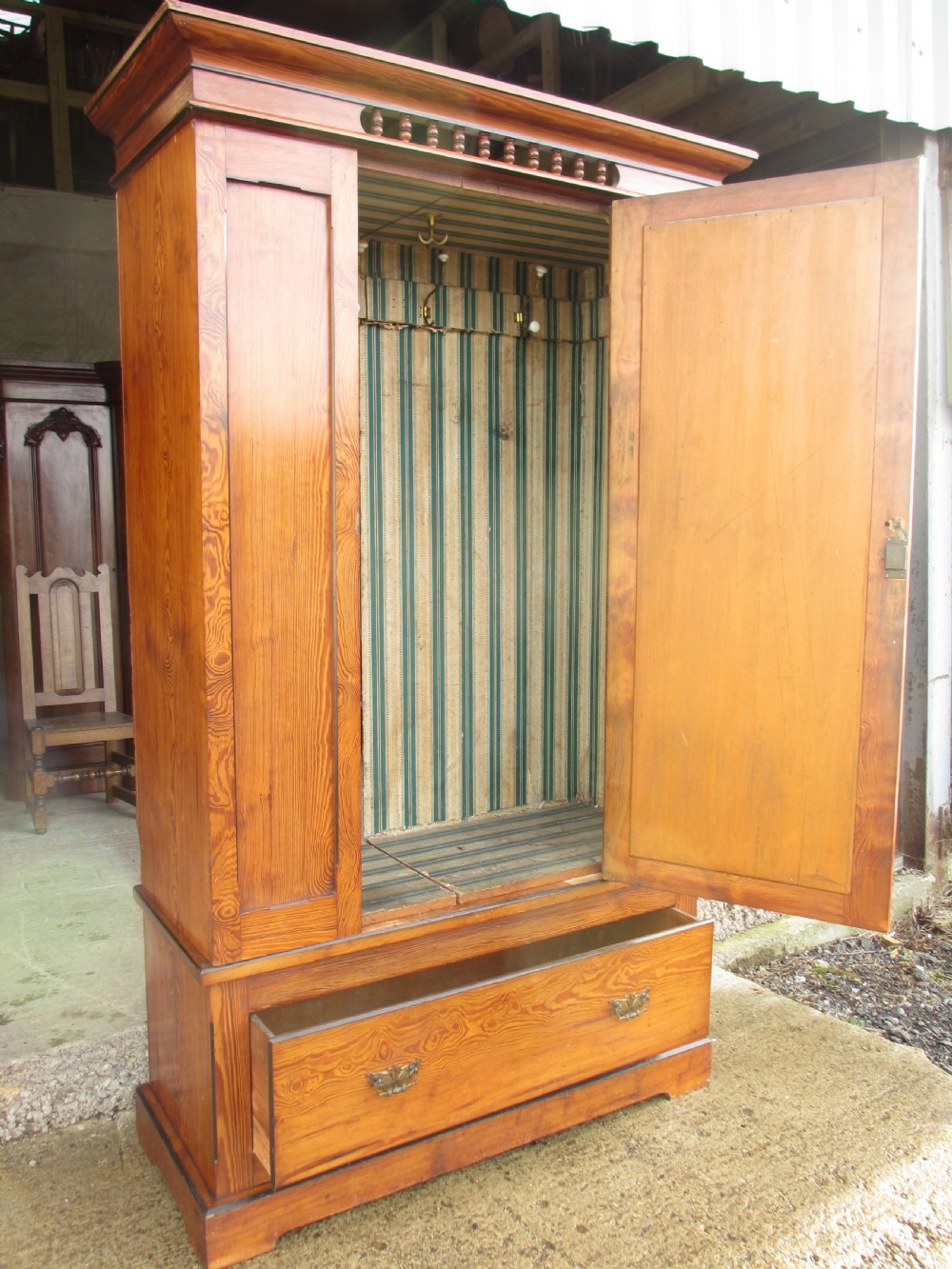 A Victorian pitch pine freestanding wardrobe featuring a central bevelled mirror door, upper spindle gallery, panelled sides, and a single lower drawer. View XII